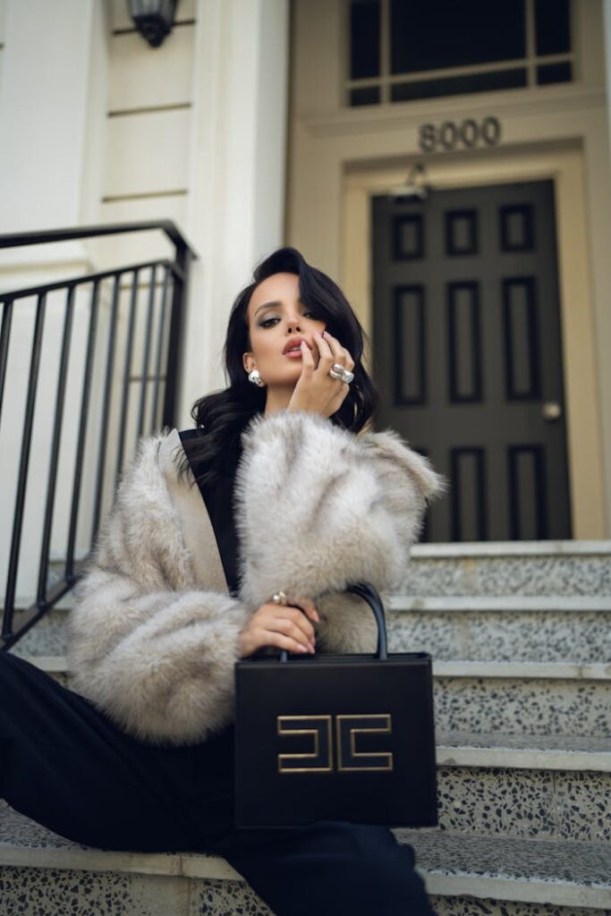 The Art of Drawing Readers In: Your attractive post title goes here Fashionable woman in fur coat poses with luxury handbag on city steps.